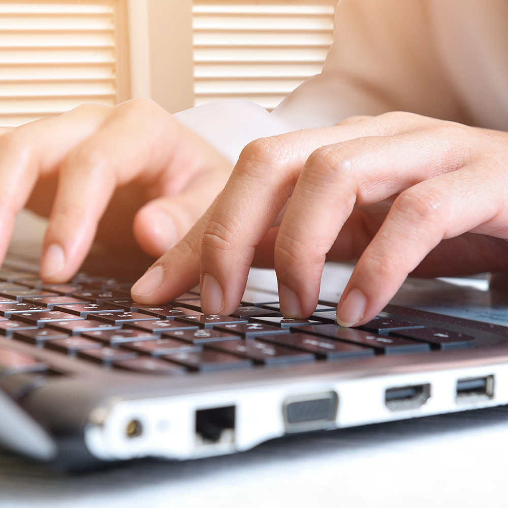 woman’s hands typing on laptop