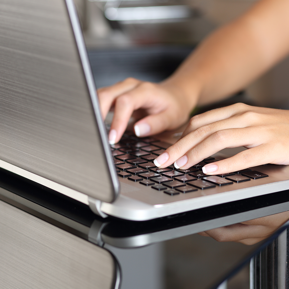 woman’s hands typing on laptop