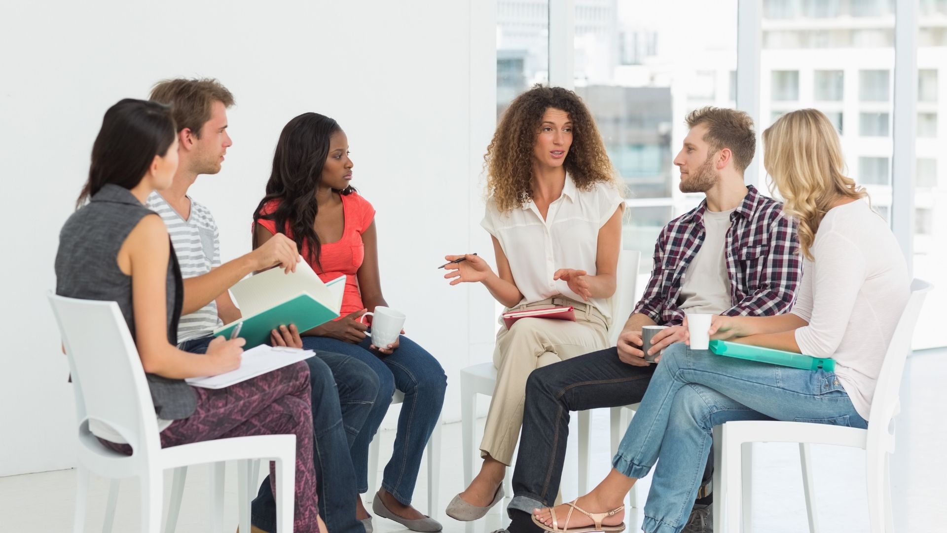 Woman leads group therapy with young adults