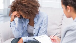 woman looks down as a therapist takes notes